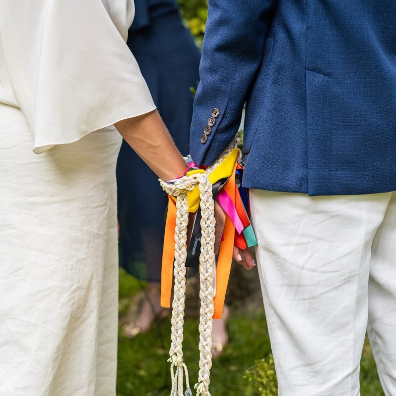 Focus sur les mains d'un couple heureux lors d'une cérémonie laïque, à Toulouse en Occitanie lors du rituel des rubans